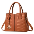 Caramel brown pebbled leather handbag with woven texture and floral charm accessory - Earthy Yellow