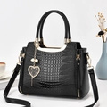 Black crocodile embossed handbag with gold heart pendant and adjustable strap - Black