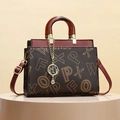 Bolso tote marrón oscuro con monograma vintage y asas ámbar en estudio fotográfico - Letras Café
