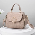 Borsa trapuntata beige con chiusura a cuore dorata su un piedistallo di marmo - Cachi