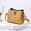 Bright yellow bucket bag with Mickey mouse charm on white geometric stands - Turmeric