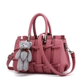 Dusty rose woven leather handbag with top handles and a plush bear pendant on white background - Dusty Pink