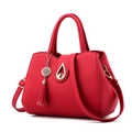 Red pebbled leather handbag with gold hardware, tassel charm, and top handles - Burgundy