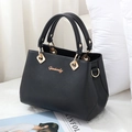 Elegante borsa a mano in pelle testurizzata nera con dettagli in metallo dorato su fondo bianco - Nero