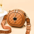 Brown round quilted crossbody bag with cat pendant and wide artistic strap on display - Earthy Yellow