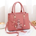 Rosafarbene PU-Leder Tote Bag mit Blumenstickerei und Schmetterlingsanhänger auf Tisch - Rosa