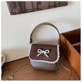 Détail d'un mini sac en cuir avec dentelle, nœud métallique et bandoulière chaîne - Marron