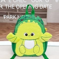 Dettaglio di uno zaino dinosauro verde con design in peluche e motivi di veicoli - Dinosauro