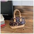 Detailed view of leopard print mini shell bag with chain strap on a wooden desk - Coffee Leopard