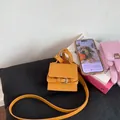 Detalle de un mini bolso amarillo de solapa con hebilla metálica sobre un cojín - Amarillo