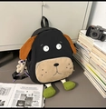 Black puppy-shaped backpack with green legs and bear charm on light gray floor - With Pendant / Large / Black