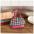Detail of pink houndstooth mini shell bag with golden chain strap on a wooden desk - Rose Red