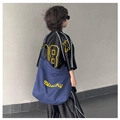 Détail du cabas en toile bleu marine avec broderie Blucky jaune et photo de mannequin - Bleu foncé (sans pendentif)