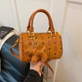 Caramel Boston mini handbag with cat print and puppy charm shown in handheld pose - Bare Bag / Yellow