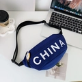 Kids navy blue crossbody bag with white China lettering and trendy charm on a desk - Large / Blue