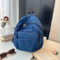 Détail du sac à dos en denim bleu avec texture, poche avant zippée et garnitures métalliques - Bleu foncé