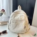 Vue détaillée d'un mini sac à dos en toile blanc cassé avec fermetures métalliques - Blanc
