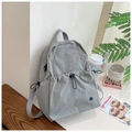 Mochila minimalista de nailon gris con bolsillos de cordón en un entorno luminoso - Gris