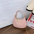 Pink crescent crossbody bag with gold chain strap and metallic logo in a cozy setting - Pink