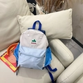 Kids color-block backpack in cream and blue with mountain logo on a leather sofa - Small / Blue