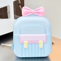 Detail of light blue hardshell backpack featuring a pink bow and yellow decorative buttons - Blue