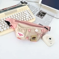 Detail of pink and beige kids chest bag featuring cartoon tags on a lifestyle background - Pink
