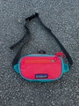 Detailansicht der Kinder-Brusttasche aus Nylon mit Kontrastfarben und Berg-Logo-Aufnäher - Rot-Grün-Patchwork