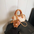 Detail of a creamy Boston bag with brown handles and a cute plush bear charm - With Pendant / Off White