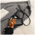 Detail of black crossbody bag with embossed letters and a cute brown bear charm - With Pendant / Black