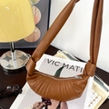 Dettaglio borsa a mezzaluna in pelle caramello con design a pieghe e tracolla annodata - Marrone