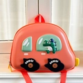 Detail eines kreativen Kinderrucksacks in Autoform mit einem niedlichen Dinosaurier - Orange
