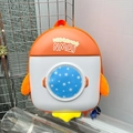 Detail view of rocket shaped kids backpack with a circular transparent window and stars - Orange