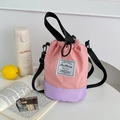 Detalle de bolso tipo cubo rosa y púrpura con cordón ajustable y etiqueta tejida de moda - Rosa