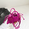 Mini magenta crossbody bag with top handle and drawstring closure shown in lifestyle context - Rose Red