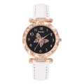 Detail of rose gold watch face with butterfly pattern and rhinestone bezel on white leather - White