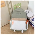 Detalle de una mochila escolar de colores con bolsillos y logotipo en un entorno cálido - Verde