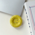 Gros plan d'un support de téléphone en forme de bouton jaune avec des taches d'encre - Taches d'encre - Jaune
