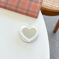 Close-up of glitter heart phone griptok with built-in makeup mirror on a white desk - White