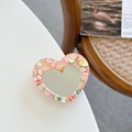 Macro shot of heart-shaped glitter mirror phone grip with fruit resin decorations - Orange