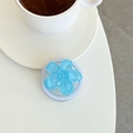 Vue rapprochée d'un support de téléphone fleur 3D bleu pailleté sur un bureau blanc - Bleu clair