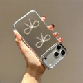 Close-up of clear phone case with 3D rhinestone bows, pearls, and a silver camera ring - Plated Mirror+2 Rhinestone Bows / iPhone 7/8/SE 2020