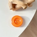 Gros plan d'un support de téléphone bouton orange brillant à quatre trous sur bureau blanc - Orange Cristal