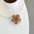 Close-up of amber glitter floral phone grip on white desk with a coffee cup - Caramel