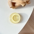 Detail of a round resin button phone grip featuring a creamy yellow cat-eye stone texture - Crystal Light Yellow