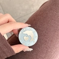 Close-up of a blue dolphin and heart glitter phone grip held in a person's hand - Glitter Dolphin Mirror / Blue