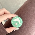 Detail of mint green phone socket with rhinestone border and dolphin motif on a hand - Glitter Dolphin Mirror / Dark Green