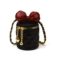 Quilted black vanity bag with a large deep red bow and gold chain strap accent - Black