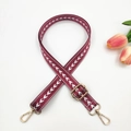 Detail view of 2.5cm burgundy nylon bag strap with white arrow pattern and gold hardware - Burgundy