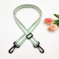 Detail of adjustable 2.5cm green and white striped bag strap with black plastic swivel hooks - Light Green + Black Buckle