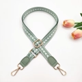 Close-up of adjustable light green woven strap with white arrow pattern and gold metal hooks - Bean Green + Bean Green Leather
